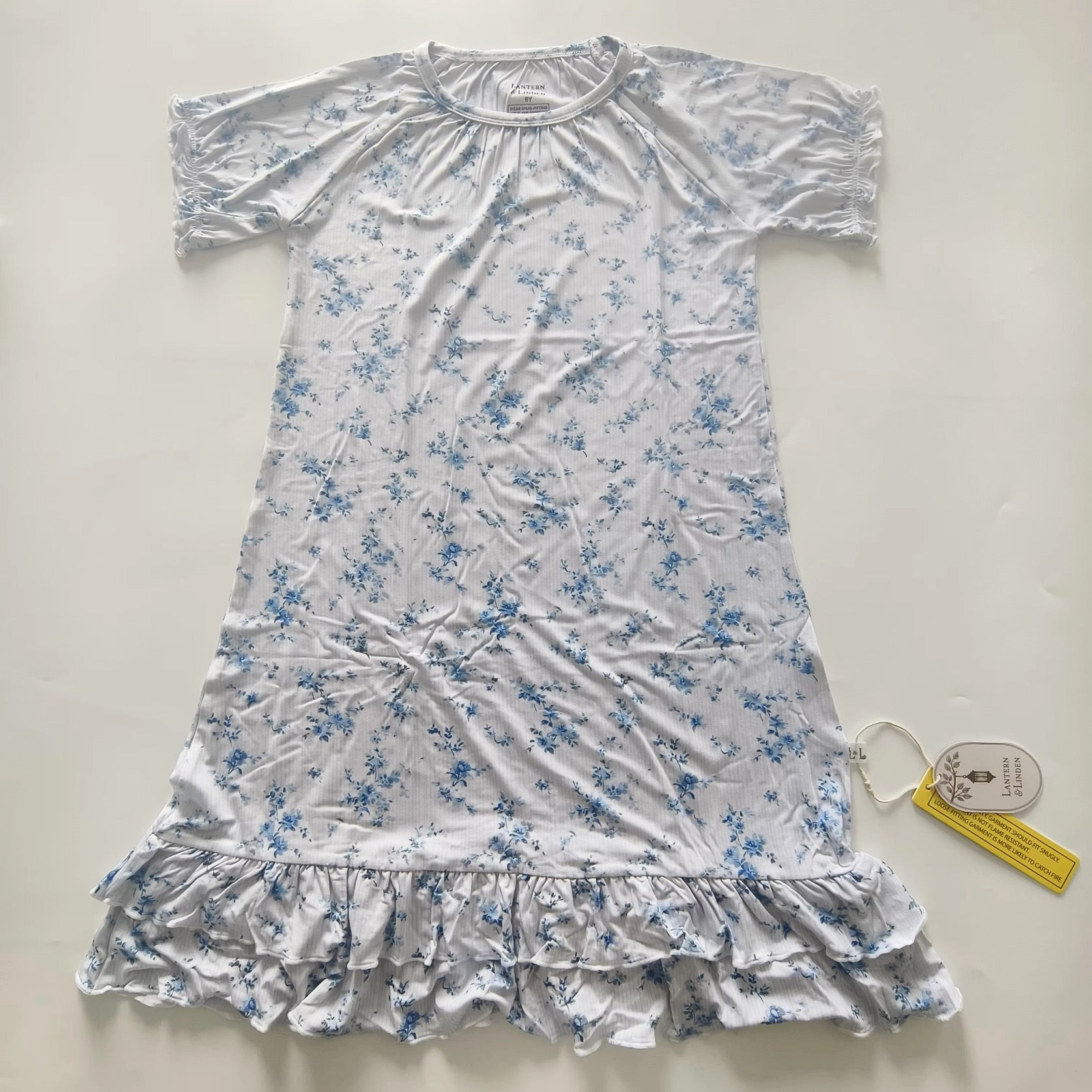 A short-sleeve bamboo nightgown with a blue floral print on a white background, featuring a ruffled hem and a gathered neckline.