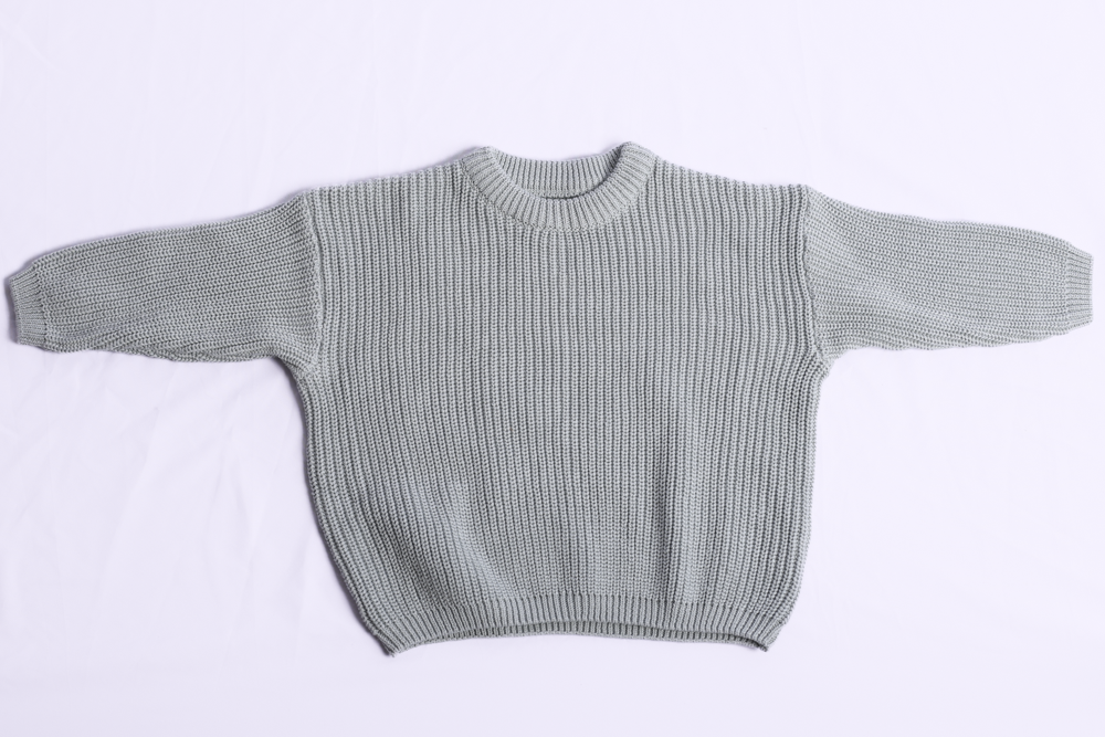 A light sage green ribbed knit sweater with long sleeves and a crew neck, laid flat against a white background.
