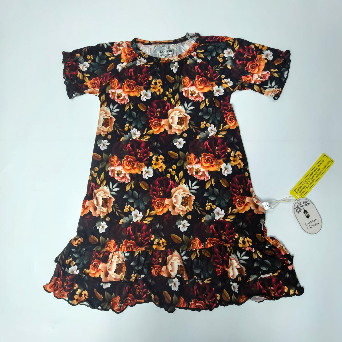 A short-sleeve black nightgown with an orange, red, and white floral print, laid flat on a white background with a yellow tag attached.